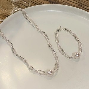 Elegant silver multi-strand pearl necklace and bracelet set on a white ceramic tray