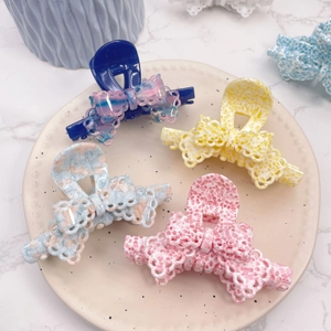 Detailed overhead view of four colorful floral patterned hair claws on a ceramic plate