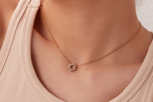 Close-up of 18K gold necklace with a circular pendant set with white cubic zirconia stones
