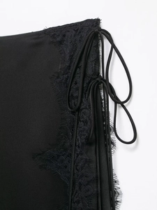 Dettaglio della gonna in raso nero con bordo in pizzo e coulisse laterale regolabile