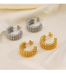 Detail of twisted rope design earrings in 18K gold and silver plating on silk fabric