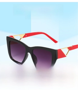 Detail of square sunglasses with black frame, red temples and gold metal accents