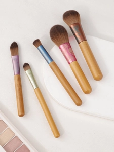 Detail view of 5 mini makeup brushes with colorful floral aluminum tubes and wooden handles