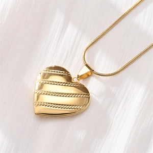 Macro shot of gold heart locket pendant with textured surface on a fine snake chain