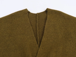 Vue macro détaillée de la maille vert olive et des coutures du col en V sur le gilet