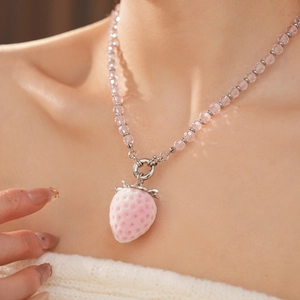 Close-up of pink strawberry pendant on a transparent beaded necklace worn by a model