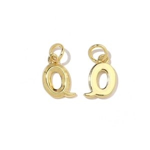 Macro detail of polished 18K gold letter Q charms with zircon inlays and loops