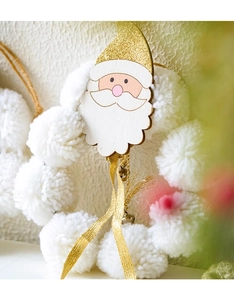 Detail of a handmade Christmas wreath with white pom poms and a glittery Santa Claus ornament