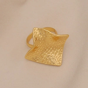 Detail of gold square ring featuring a unique hammered texture on a textured fabric