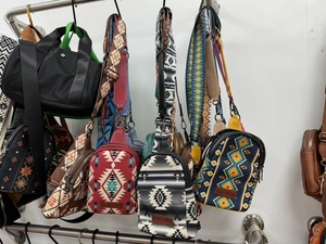 Detailed display of ethnic style canvas crossbody bags with geometric patterns on a rack