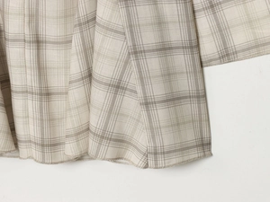 Macro view of woven plaid fabric texture and hem stitching on V-neck dress