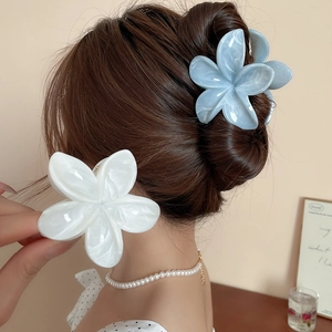 Détail de pinces à cheveux fleurs en acrylique bleu et blanc portées avec un éclairage doux