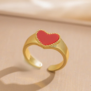 Macro detail of adjustable gold ring featuring a red heart with tiny bead edging