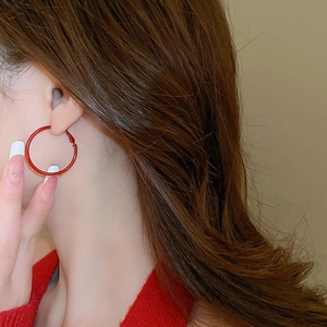 Close-up of minimalist deep red hoop earrings on model for a trendy and elegant winter look