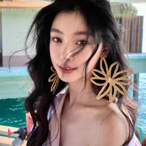 Close-up of golden fan-shaped raffia earrings with intricate woven mesh texture details