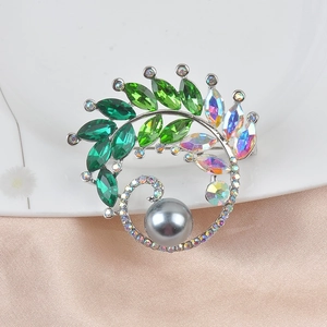 Detail of luxury green crystal brooch with a grey pearl on soft silk fabric