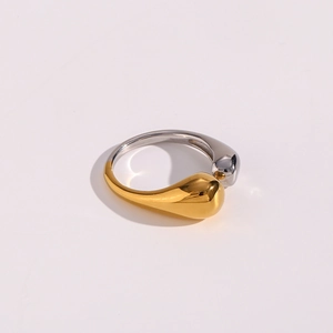Macro shot of two-tone gold and silver drop-shaped crossover ring on pink background