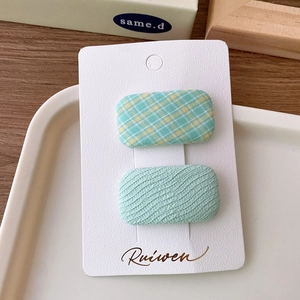 Detailed view of two rectangular macaron fabric hair clips on a white card display