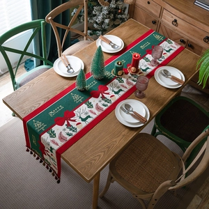 Christmas table runner with reindeer motifs and tassels on a wooden dining table