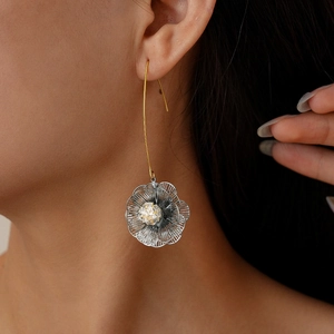 Detailed close-up of a 18K gold-plated hollow flower earring worn by a female model