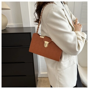 Detailed view of a brown quilted shoulder bag with gold chain strap and metal lock
