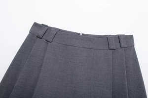 Detail view of the low-waist pleated grey mini skirt showing belt loops and side hidden zipper