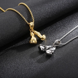 Detailed close-up of gold and silver steel boxing glove pendants on black textured background