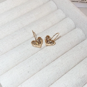 Macro shot of gold-plated heart earrings with pleated texture in a velvet jewelry box