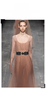 Detailed view of black elastic waist belt with gold C-buckle on a sequin dress