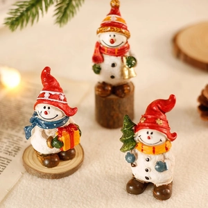 Drei Schneemann-Figuren aus Harz mit bunten Accessoires auf Holzsockeln für Weihnachten