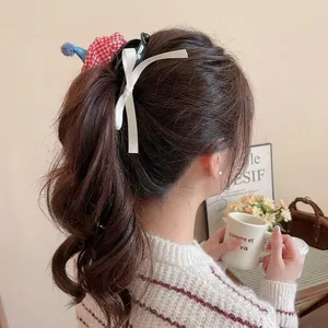Cute red checkered fabric hair claw clip with white ribbon bow on a high ponytail