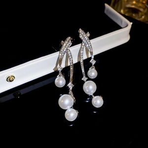 Vue macro de boucles d'oreilles pendantes argentées avec cristaux et perles blanches