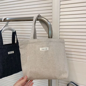Detail of minimalist canvas tote bags with 'simple wish' label in beige and navy blue