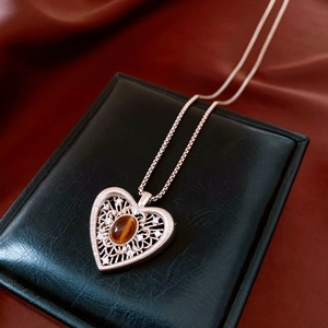 Detail of rose gold heart pendant with brown gemstone on a black jewelry box