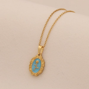 Macro shot of gold vintage floral relief pendant on blue enamel with a fine chain