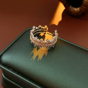 Detailed close-up of a zircon crown ring casting a shadow on a green leather box