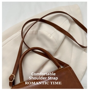 Detail of adjustable strap with gold buckle and smooth handle on brown vintage handbag