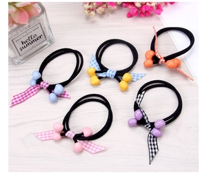 Detail of five cute cherry hair ties with checkered bows in various colors on wood