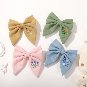 Vue détaillée des broderies florales sur barrettes à nœuds en coton et lin de quatre couleurs