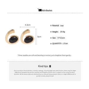 Detailed view of gold geometric oval earrings with black stones and sizing specifications