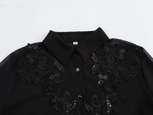 Detailed close-up of floral embroidery with beads and sequins on black chiffon shirt