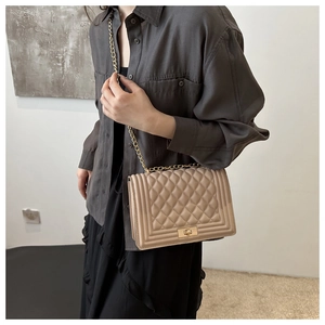 Close-up of khaki quilted crossbody bag with metal chain strap and rectangular lock detail