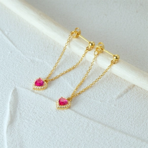 Detailed macro view of S925 silver heart drop earrings with pink gems and gold chains
