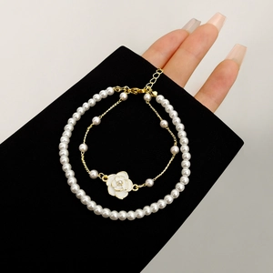 Detail of a gold-plated camellia flower and pearl double-layer bracelet set for women