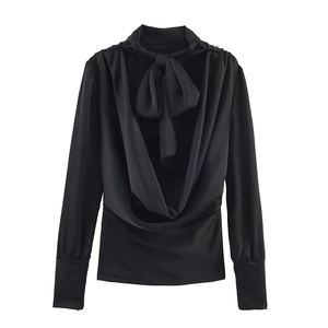 Detailed view of black satin blouse with elegant bow tie neck and draped cowl design