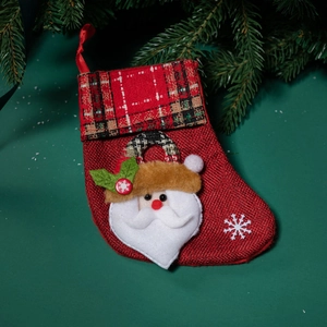 Red Christmas stocking with Santa Claus applique on dark green pine branch background
