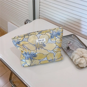 Close-up of yellow floral cosmetic bag with simple wish label on a white countertop