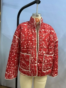 Detail of red quilted jacket showing white paisley floral pattern and front pockets