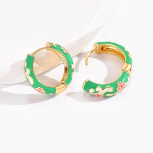 Macro detail of Chinese style gold hoop earrings with green enamel and flower pattern