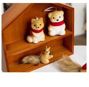 Three plush beige squirrel and bear ornaments with red scarves in a wooden display